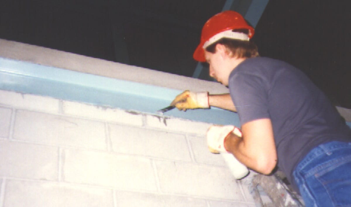 A worker running a bead of sealant along a joint