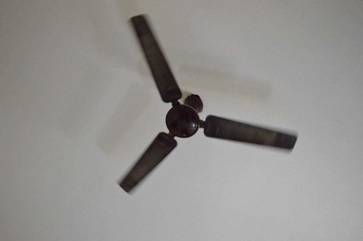 A ceiling fan turning, blades blurred with motion