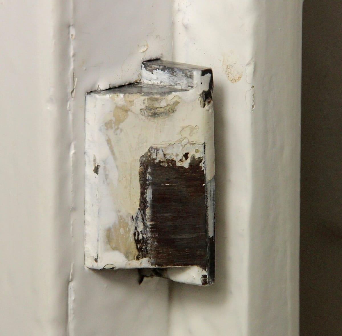 The spring latch bolt extended from the edge of a white painted door