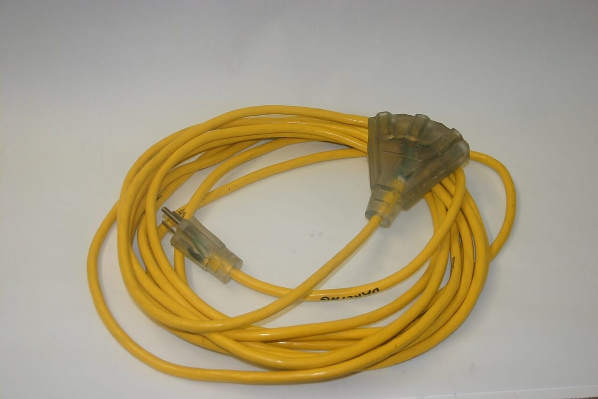 A coiled yellow heavy-duty extension cord with a three-outlet end