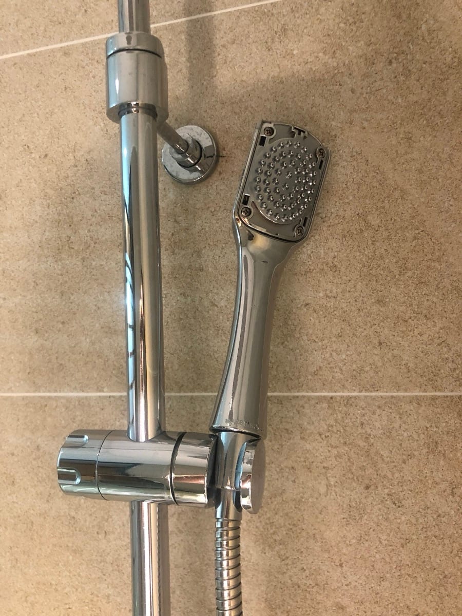 A handheld shower head on a chrome riser rail
