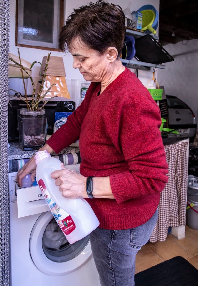 Someone cleaning a front-loading washing machine with a spray bottle