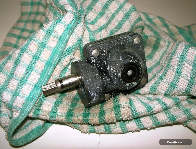 A worn faucet cartridge removed from a tap, resting on a cloth