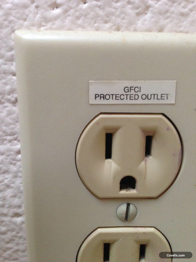 A wall outlet with a GFCI PROTECTED OUTLET label above it