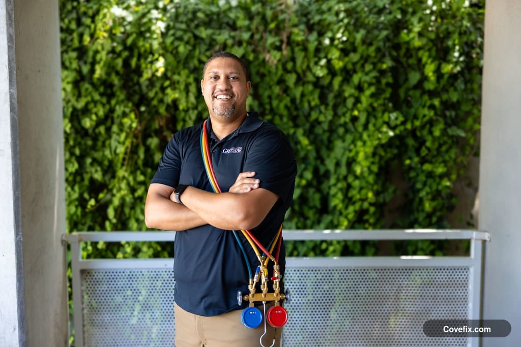 An HVAC technician holding refrigerant manifold gauges