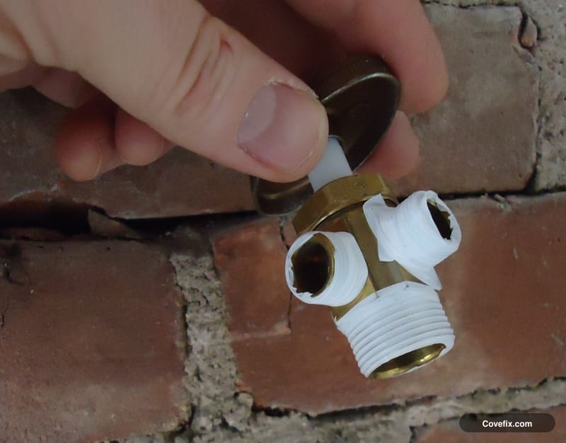 White PTFE tape wrapped around the threads of a brass hose bib fitting